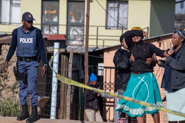 A relative of one of the victims cries as south African Police Service officers refuse to let her cross the police barrier and enter the crime scene in Soweto, South Africa,