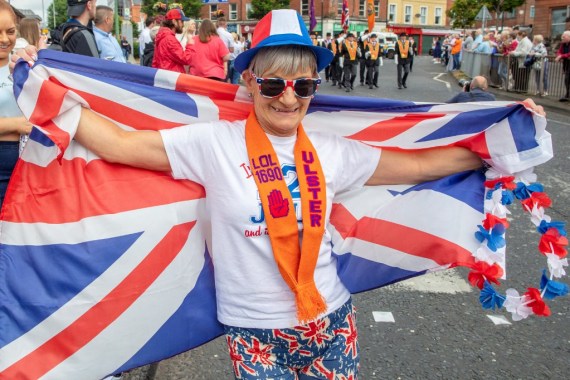 A spectator poses with a Union Jack flag during an Orange Order parade in Belfast