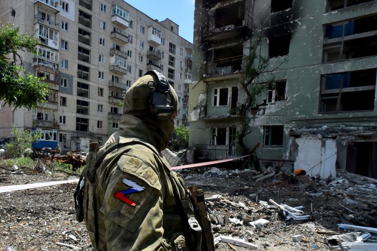 A Russian serviceman patrols a destroyed residential area in the city of Severodonetsk on July 12, 2022, amid the ongoing Russian military action in Ukraine