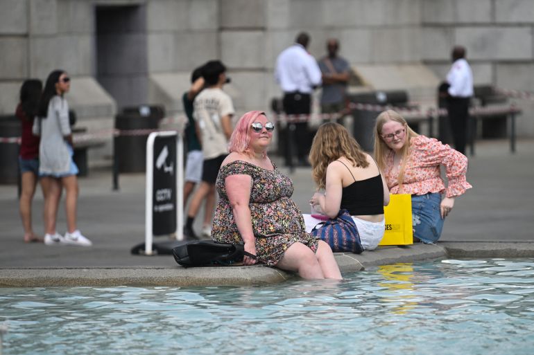 Pedestrians cool off with their feet in the water of the Trafalgar Square fountain, in central London,