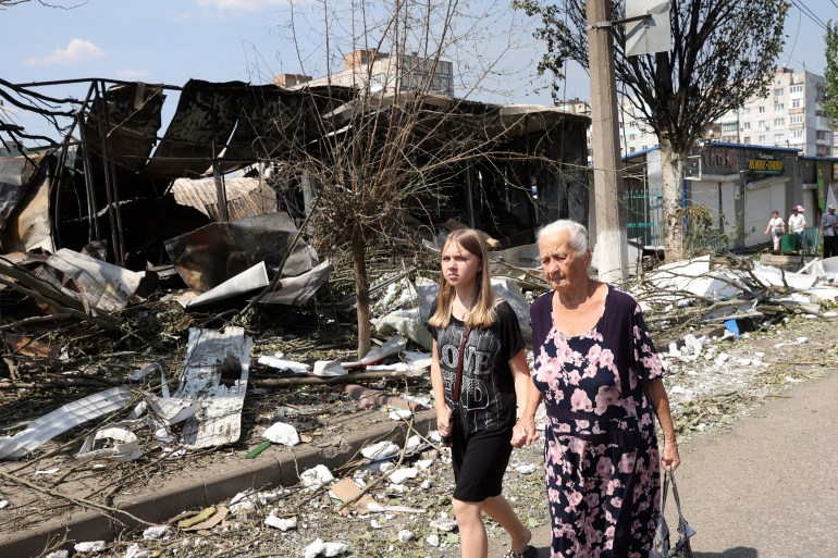 A girl and an elderly lady walk among the debris of a destroyed local market after a Russian missile strike in the town of Bakhmut, Donetsk region on July 16, 2022
