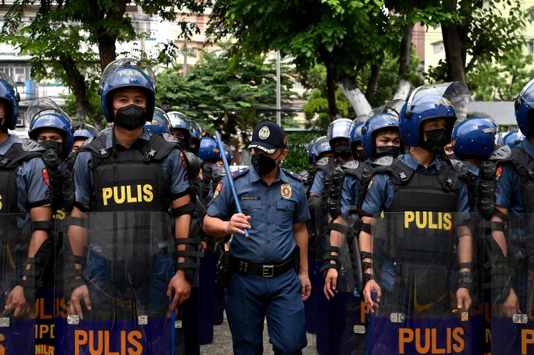 la police aux philippines porte un équipement anti-émeute (avec le mot «pulis» sur leurs gilets) alors qu'ils se préparent pour le discours de la SONA de lundi