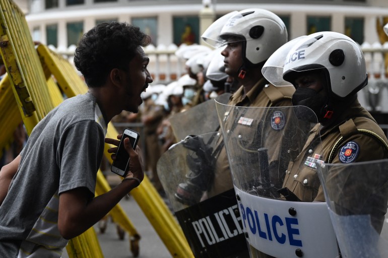 A demonstrators interacts with Police special task force personnel standing guard while blocking a road as demonstrators take part in a protest march against Sri Lankan President Ranil Wickremesinghe.