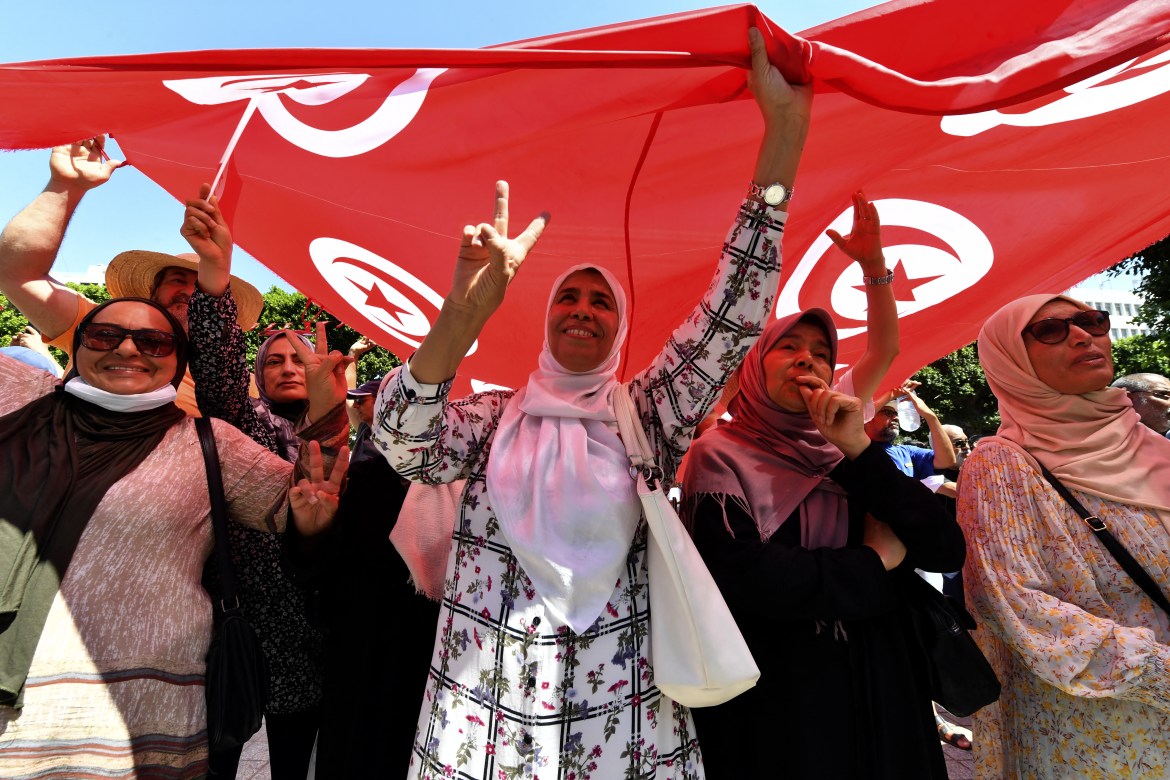 Tunisian protesters raise a flag