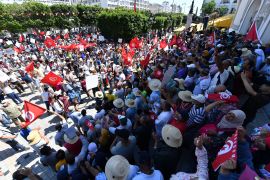 Tunisian protesters raise flags and placards