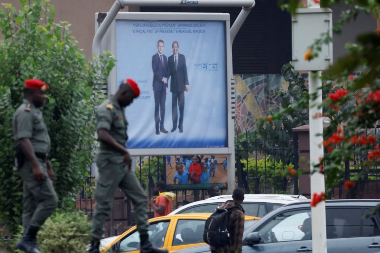 Pedestrians walk past a poster displaying Cameroonian President Paul Biya next to his French counterpart Emmanuel Macron