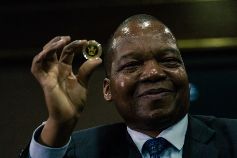 Zimbabwe Reserve Bank governor John Mangudya displays the country's new Mosi-oa-Tunya gold coin.