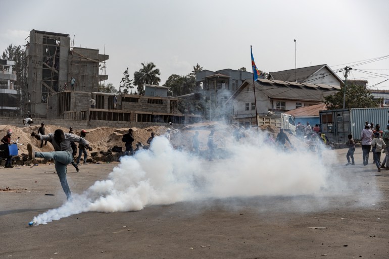 A demonstrator kicks a tear gas canister during a protest against the peacekeeping mission