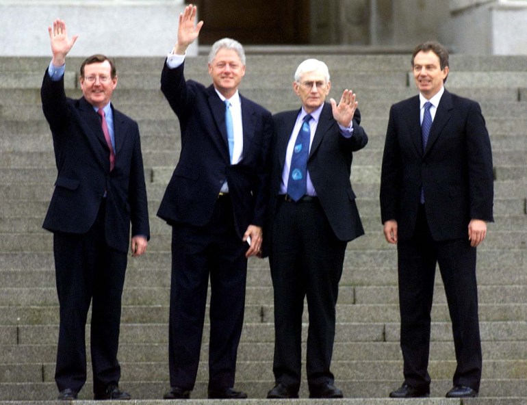 In 2000, Northern Ireland First Minister David Trimble, US President Bill Clinton, Northern Ireland's Deputy First Minister Seamus Mallon and the UK's Prime Minister Tony Blair stand and wave on the steps of Stormont parliamentary buildings in Northern Ireland.