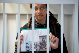 US WNBA basketball superstar Brittney Griner holds photographs standing inside a defendants' cage before a hearing at the Khimki Court, outside Moscow on July 26, 2022. - Griner, a two-time Olympic gold medallist and WNBA champion, was detained at Moscow airport in February on charges of carrying in her luggage vape cartridges with cannabis oil, which could carry a 10-year prison sentence. (Photo by Alexander Zemlianichenko / POOL / AFP)