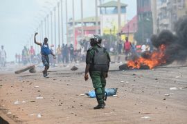 A protester on a street in Conakry throws a rock towards a police officer.
