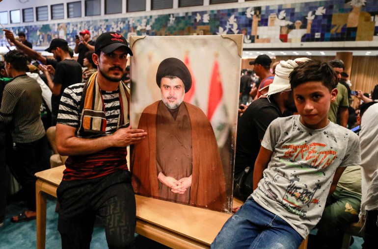 Iraklı din adamı Mukteda Sadr'ın destekçileri, ülkenin parlamentosunda liderlerinin bir fotoğrafını tutuyorlar.
