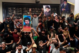 Supporters of the Iraqi cleric Moqtada Sadr raise portraits of their leader inside the country's parliament in the capital Baghdad's high-security Green Zone, as they protest against a rival bloc's nomination for prime minister, on July 30, 2022. - The protests are the latest challenge for oil-rich Iraq, which remains mired in a political and a socioeconomic crisis despite elevated global energy prices. Sadr's bloc emerged from elections in October as the biggest parliamentary faction, but was still far short of a majority and, nine months on, deadlock persists over the establishment of a new government. (Photo by Ahmad Al-Rubaye / AFP)