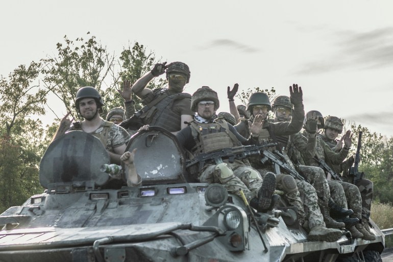 Ukranian soldiers sit a top of an armoured vehicle as it drives to frontline on the outskirts of Bakhmut