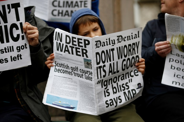 A protester reads a mock-up newspaper as they block the road during an Extinction Rebellion demonstration at Bank, in the City of London, Britain October 14, 2019.