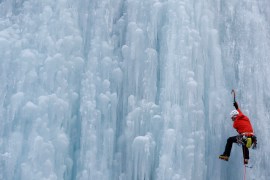 An Italian alpine rescuer climbs a frozen waterfall in 2020 in Malga Ciapela in the Dolomites - part of the Italian Alps, which are heavily affected by climate change, with a constant temperature increase and more extreme weather fronts resulting in shrinking glaciers and a greater risk of avalanches [Yara Nardi/Reuters]