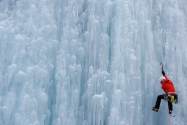An Italian alpine rescuer climbs a frozen waterfall in Malga Ciapela in Italy's Dolomites in 2020. The Italian Alps are heavily affected by climate change with a constant temperature increase and more extreme weather fronts, resulting in shrinking glaciers and the risk of avalanches becoming more common [Yara Nardi/Reuters]