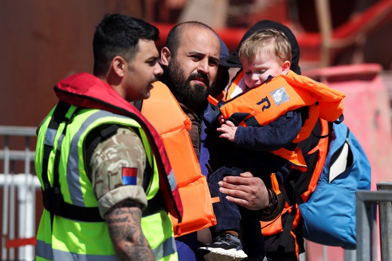 A man is seen carrying a child after arriving at the Port of Dover in southeastern England