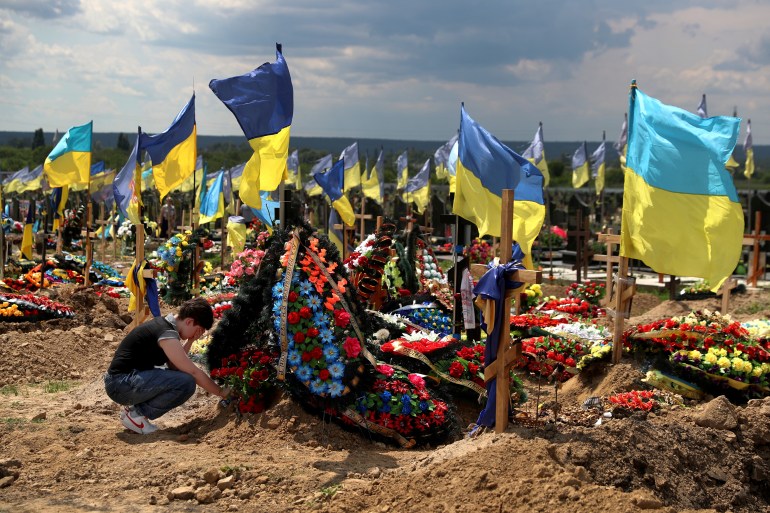 A woman reacts next to a grave of Evgeny Khrapko, a combat medic and instructor of tactical medicine who was killed in a mission, amid Russia's attack on Ukraine, after his farewell ceremony in Kharkiv, Ukraine June 14, 2022. REUTERS/Ivan Alvarado
