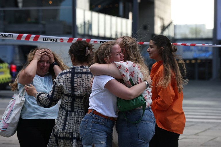 덴마크 경찰이 코펜하겐에서 현장에서 총격 사건이 발생했다는 보고를 받은 후 사람들이 필즈 쇼핑센터 밖에서 포옹하고 있다.