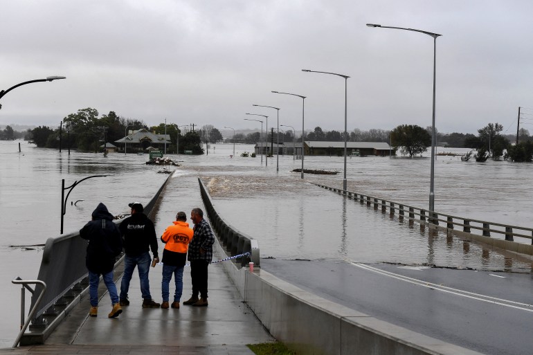 People look on as the Windsor Bridge is submerged under floodwater from the swollen Hawkesbury River in Windsor, north west of Sydney, Australia, July 4, 2022.