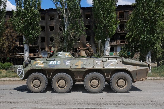 Service members of pro-Russian troops ride on top of an armoured personnel carrier in the Luhansk Region.