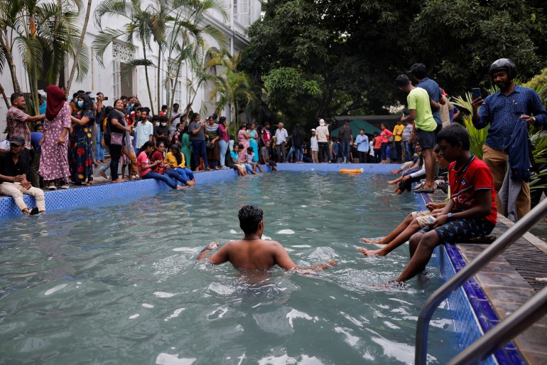 A man stands in the swimming pool as people occupy the president's residence [