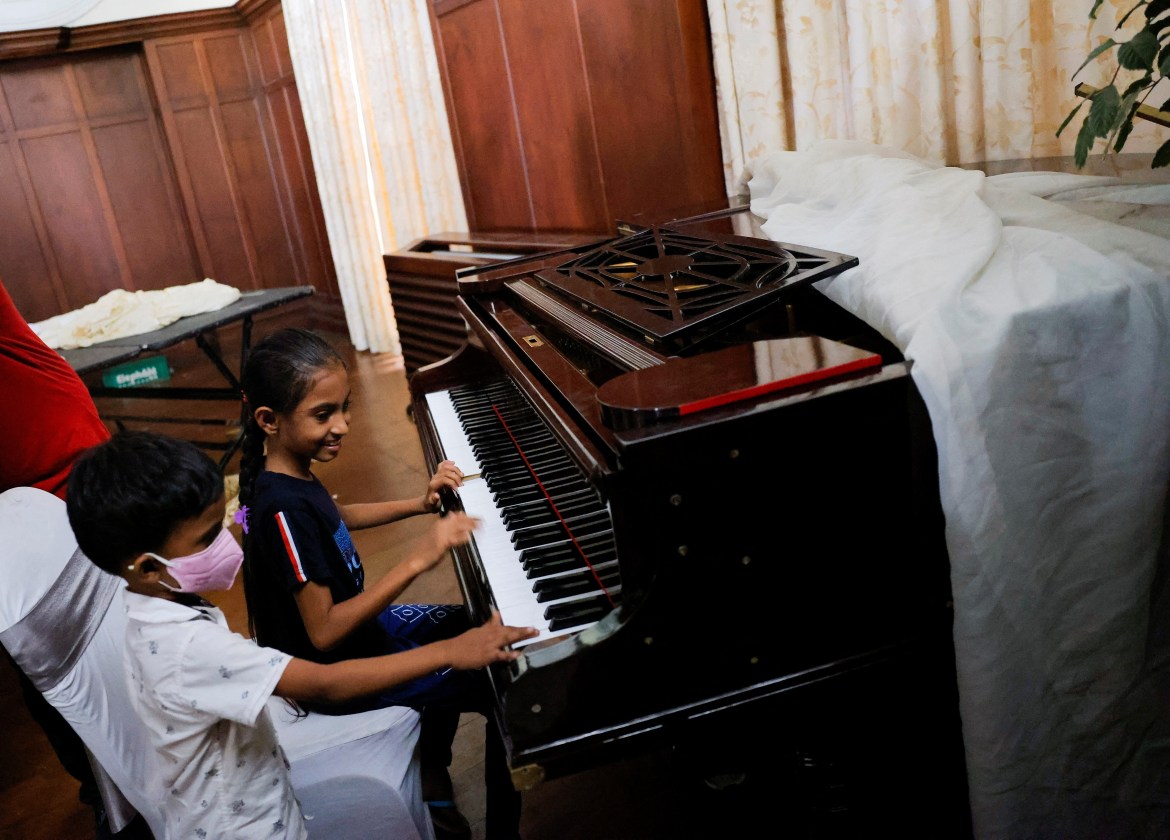 Two kids play the piano inside the President's house