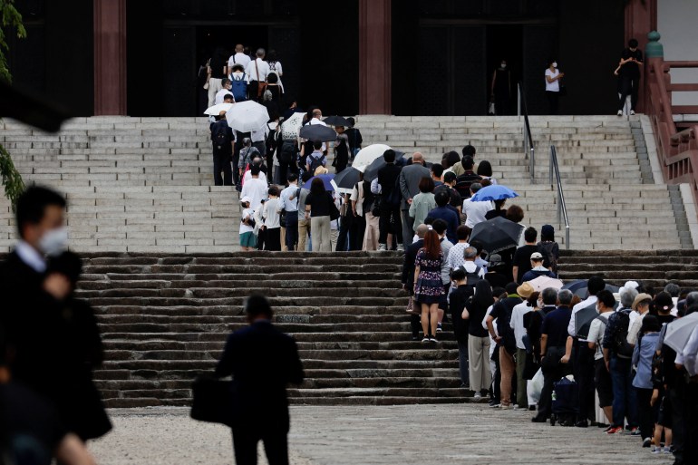 People queue on the steps of the Zojoji temple to pay their respects to former prime minister Shinzo Abe