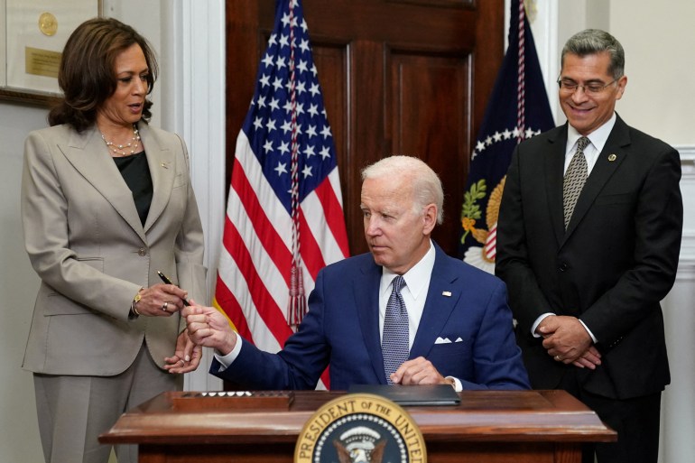 U.S. President Joe Biden hands the pen to Vice President Kamala Harris as Health and Human Services Secretary Xavier Becerra stands near