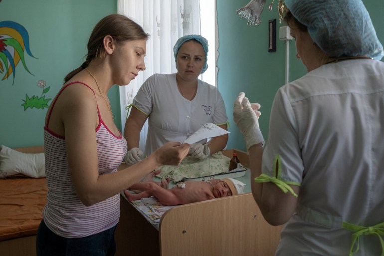 Marina Tupata, 26, stands next to her six-day-old baby Sofia