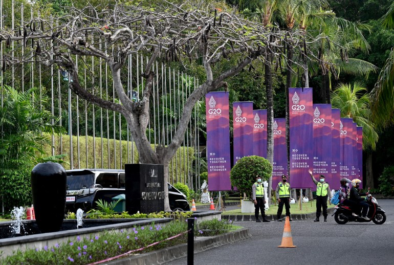 Polis, Endonezya'nın tatil beldesi Bali'deki Nusa Dua'daki G20 Maliye Bakanları Toplantısı için bir mekanın yakınında G20 zirvesinin pankartlarının önünde duruyor.