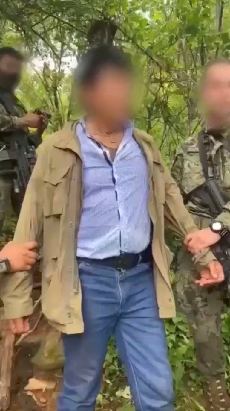 Rafael Caro Quintero, in jeans, a pale blue shirt and khaki coloured jacket as he is detained by the Mexican Navy