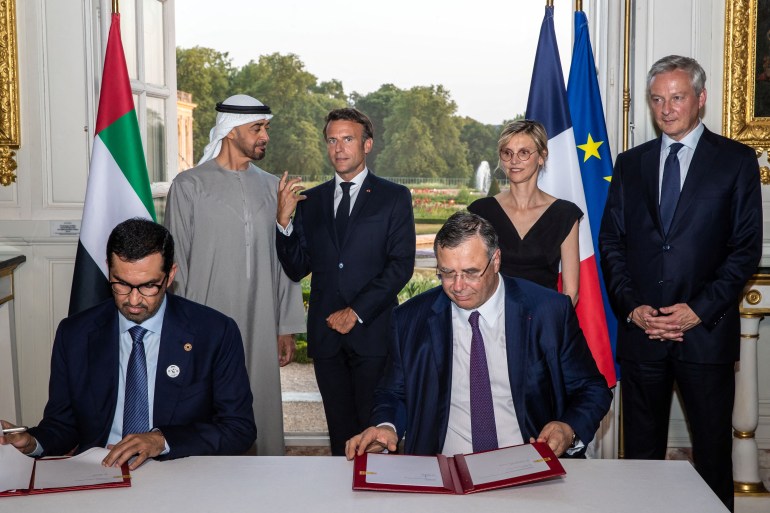 French President Emmanuel Macron and United Arab Emirates’ President Sheikh Mohammed Bin Zayed speak as UAE Industry Minister Sultan Ahmed Al Jaber and TotalEnergy Group CEO Patrick Pouyanne sign documents during a signing ceremony before a state dinner at the Grand Trianon of the Versailles castle near Paris