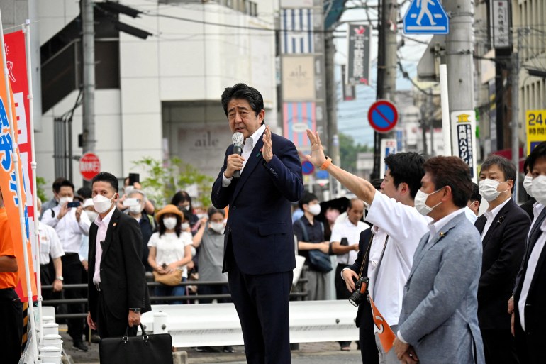 Shinzo Abe in dark suit and white shirt, speaks to a group of people at an informal campaign stop in Nara 