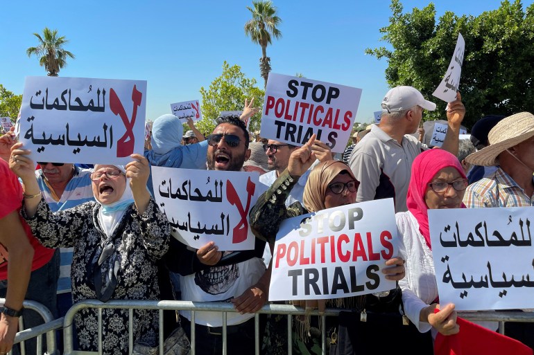Protesters holding banners saying 'stop political trials' behind a barricade in Tunis