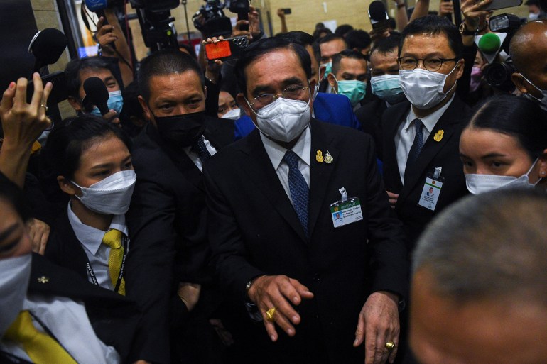 Thai PM Prayuth Chan-ocha in a dark suit and tight-fitting face mask arrives at parliament for the confidence vote