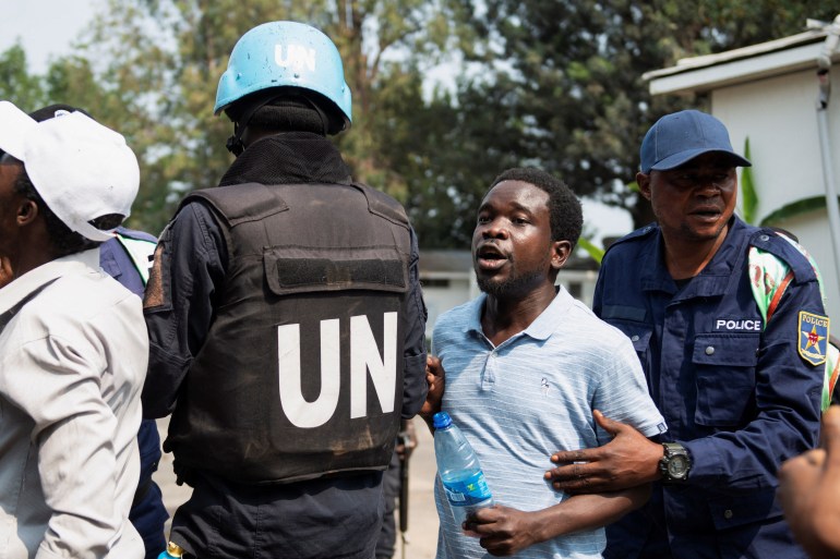 A Congolese policeman and a United Nations Organization Stabilization Mission in the Democratic Republic of the Congo (MONUSCO) peacekeeper attempt to stop protesters inside the compound of a United Nations peacekeeping force's warehouse in Goma in the North Kivu province of the Democratic Republic of Congo