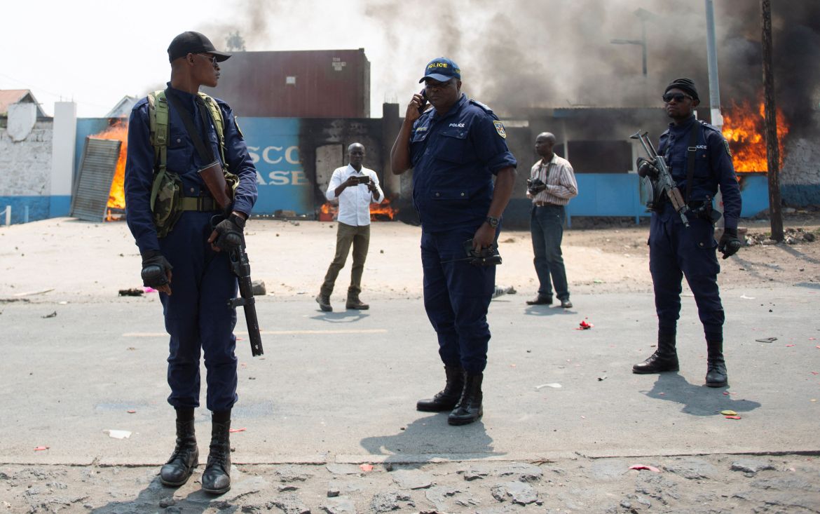 Congolese policemen stand guard to stop protesters outside the compound of a United Nations peacekeeping force's warehouse
