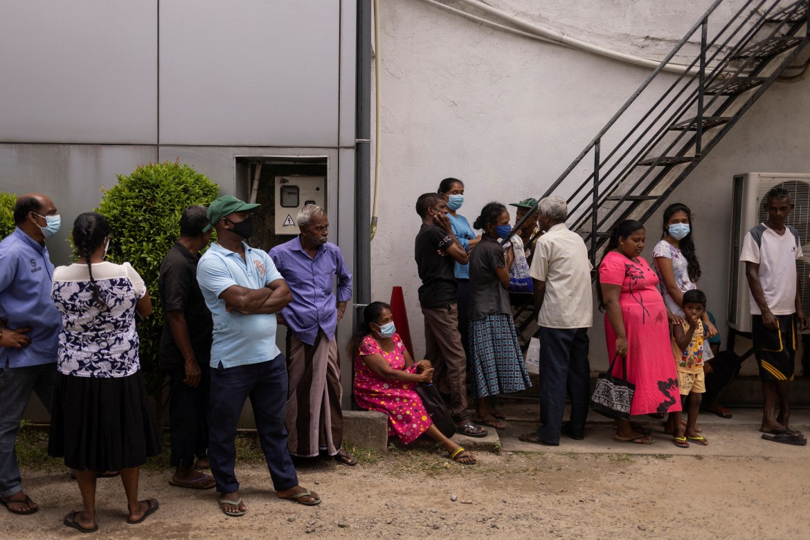 People stand in a queue to receive food at a community kitchen