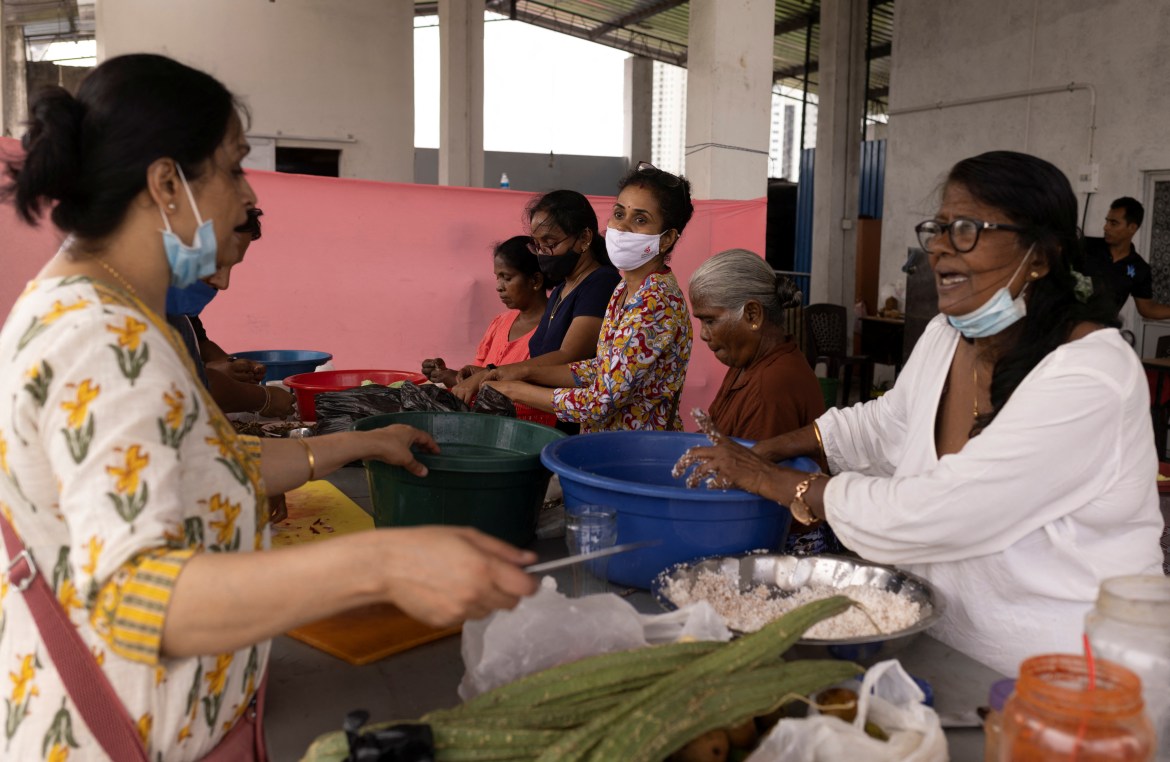 Volunteers cut vegetables to prepare food inside a community kitchen