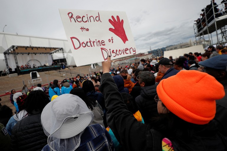 A person holds a sign that reads 'Rescind the Doctrine of Discovery' as Pope Francis speaks in Iqaluit