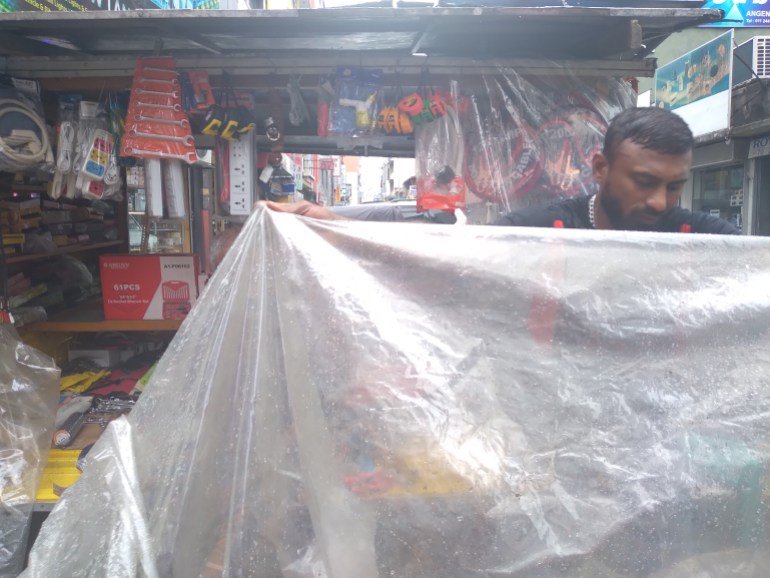 A man covers his goods with a plastic sheet in a market in Sri Lanka