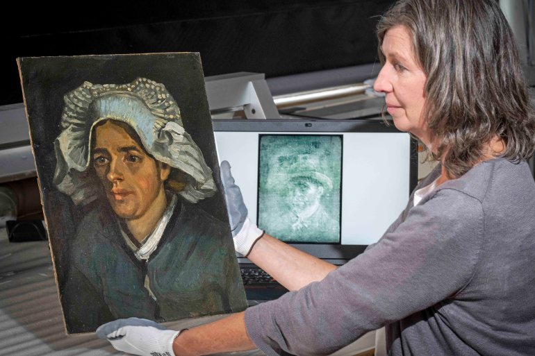 A painting conservator looks at the image behind the canvas through a an X-ray image through a specially designed lightbox.
