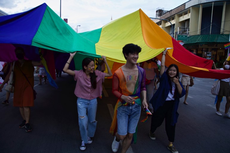 People parade beneath a Pride flag during celebrations in the Thai city of Chiang Mai