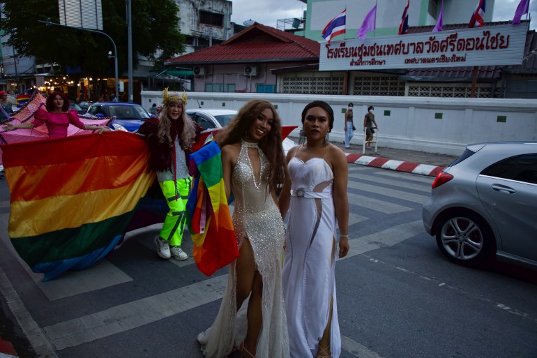 Chiang Mai Pride participants pose for the camera in long white gowns as they walk along the city's streets
