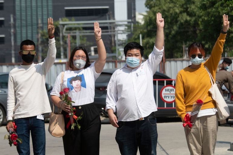 Pro-democracy activists, from left, Panupong Jadnok, Panusaya Sithijirawattanakul, Parit Chiwarak, and Benja Apan, gesture with a three-fingers salute, a symbol of resistance as they walk to Pathumwan police station in Bangkok, Thailand, Wednesday, Jan. 20, 2021. Six pro-democracy activists, including two 17-year old minors, report to police after being issued summonses to answer charges of lese majeste or defaming or insulting key members of the royal family. (AP Photo/Sakchai Lalit)