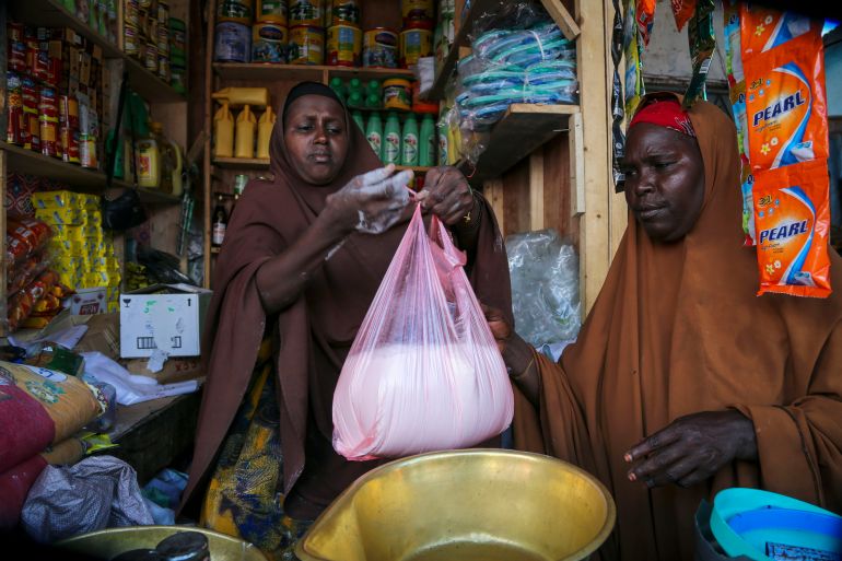 Halimo Hersi, 42, right, buys wheat flour from a shopkeeper in the Hamar-Weyne market in the capital Mogadishu, Somalia