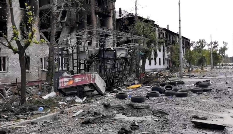 Ukrayna'nın Lysychansk kentinde yola enkaz saçılmış hasarlı konut binaları.