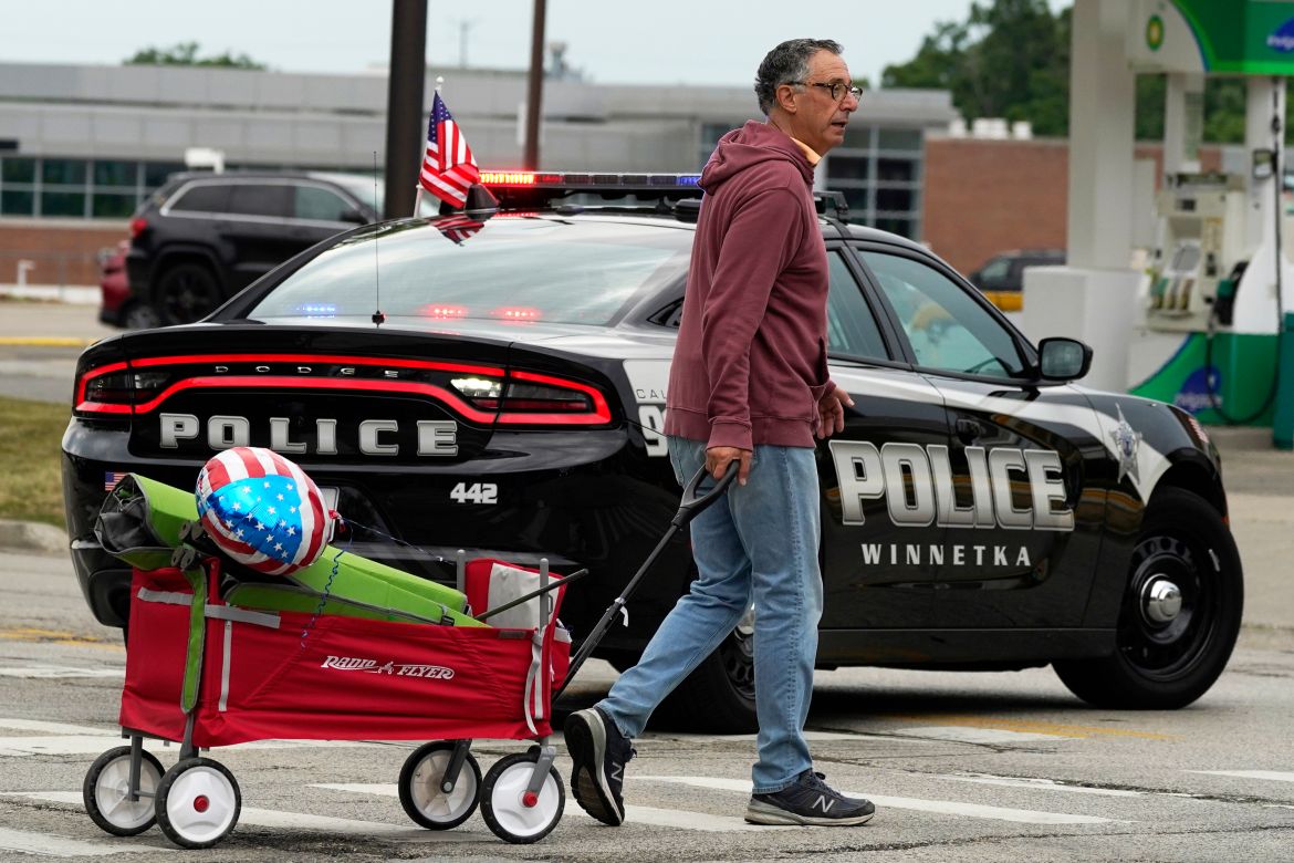 A man carries his belongings after a mass shooting at the Highland Park Fourth of July